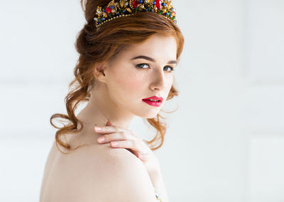 Portrait of young woman looking away against white background