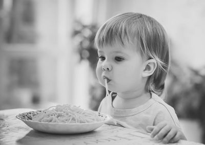 Charming baby girl eating spaghetti by hands