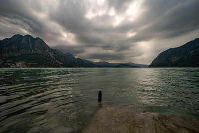 Scenic view of sea by mountains against sky