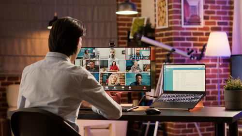 Rear view of man using laptop at table