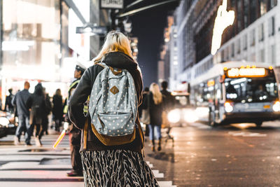 Rear view of woman walking on city street at night