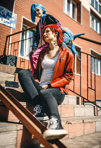 Side view of young woman sitting on railing