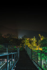 Footpath amidst trees against sky at night