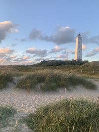 Lighthouse on field against sky