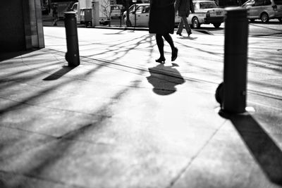 Low section of woman walking on sidewalk in city