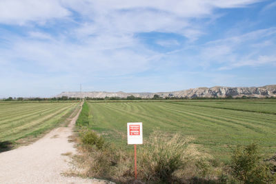 Road sign on field against sky