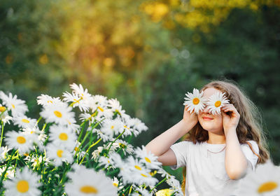 Child with daisy eyes on green background in a summer park. healthy lifestyle concept.