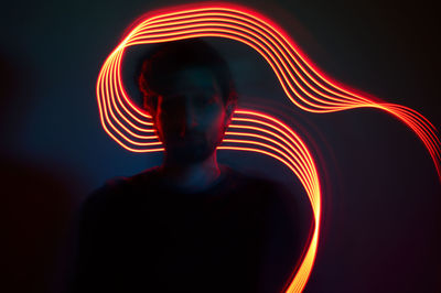 Young man with illuminated light trail against wall