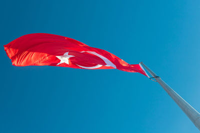 Low angle view of flag against clear blue sky