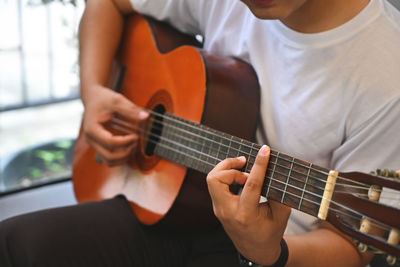 Midsection of man playing guitar