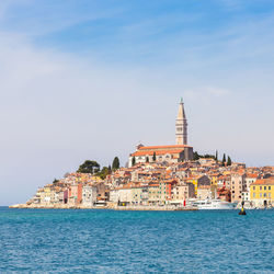 View of buildings by sea against sky in city