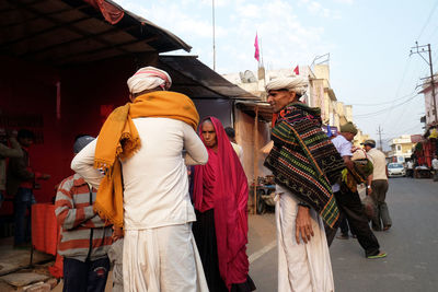 Rear view of people walking on street in city