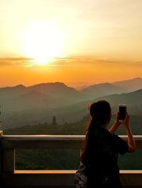 Woman photographing sunset