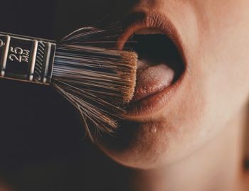 Close-up of person licking paintbrush
