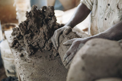 Midsection of worker kneading clay at table in workshop