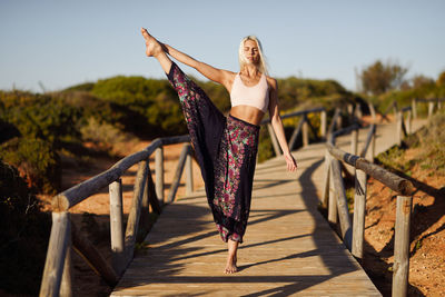 Young woman exercising while standing on footbridge