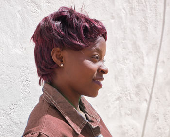 Portrait of a young woman looking away against wall