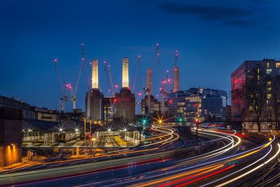 Light trails in factory against sky at night