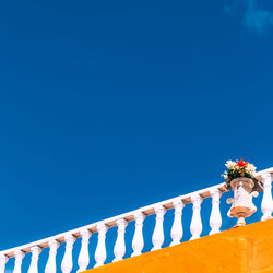 Low angle view of railing against blue sky