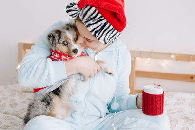 Midsection of woman with dog sitting at home