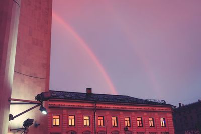 Low angle view of rainbow over building against sky