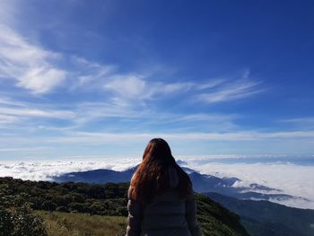 Rear view of woman standing on mountain against sky