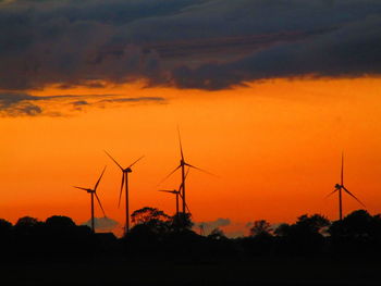 Silhouette wind turbine against sky during sunset