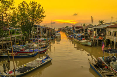 Fishing boats moored in canal during sunset