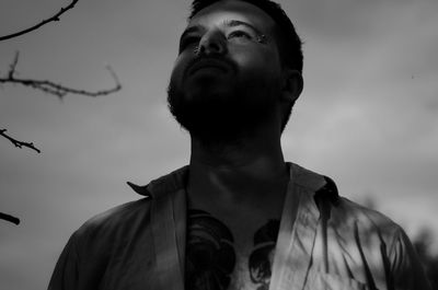 Portrait of young man looking away against sky