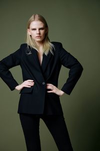 Portrait of young businesswoman standing against black background