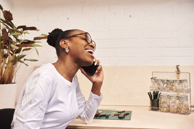 Smiling businesswoman talking on phone while sitting at office