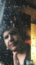 Portrait of woman seen through wet glass window