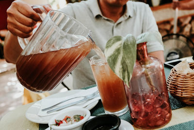 Midsection of man pouring drink in glass