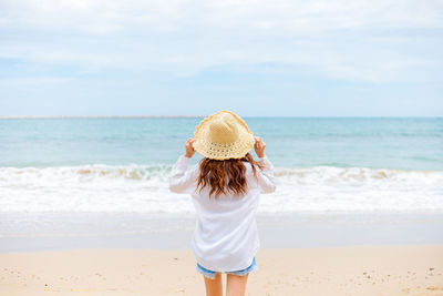 Rear view of young woman standing on beach