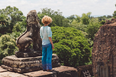Woman standing by old ruin statue