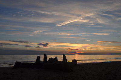 Silhouette sandcastle at beach during sunset
