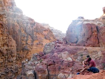 Woman on rock formation against clear sky