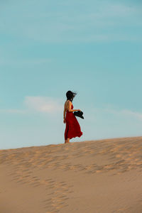 Woman standing at desert against sky