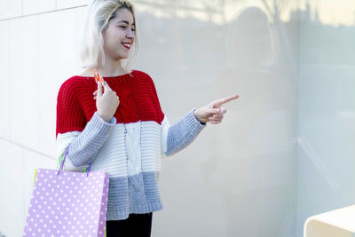 Young woman standing against wall