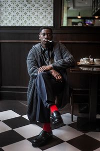 Portrait of young man sitting on tiled floor