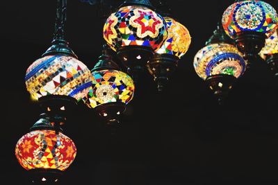 Low angle view of illuminated lighting equipment against black background
