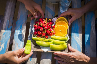 Cropped hands of people with fruits on table