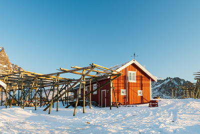 Houses on snow covered land against clear sky during winter