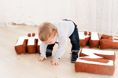 Baby boy playing on wooden floor at home