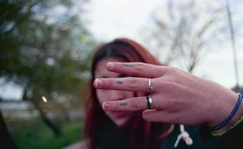 Close-up of woman gesturing with tattooed fingers