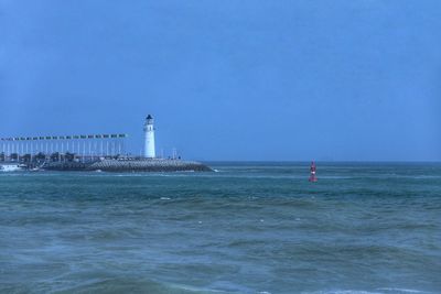 Lighthouse by sea against sky