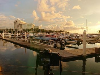 Boats moored at harbor against sky in city