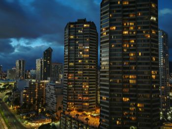 Illuminated buildings in city against sky at dusk