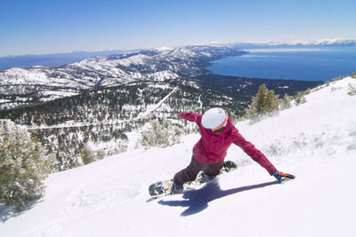 High angle view of female snowboarder descending from snowcapped mountain