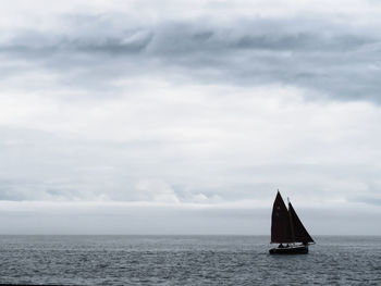 Sailboat sailing on sea against sky